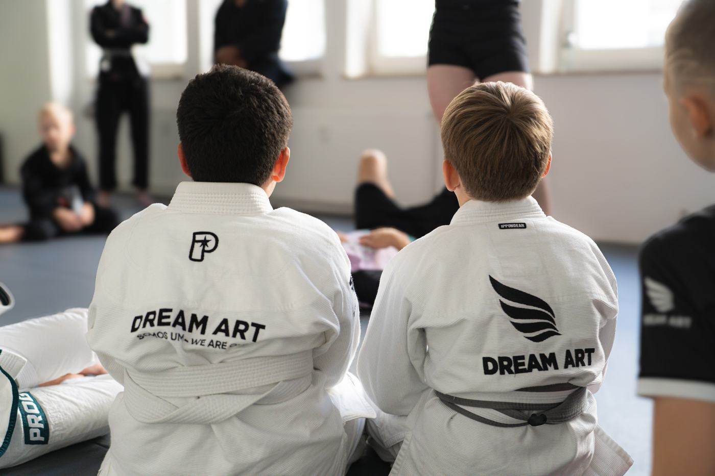 Zwei Kinder im weißen Dream-Art-Gi von hinten, sie schauen dem Training zu